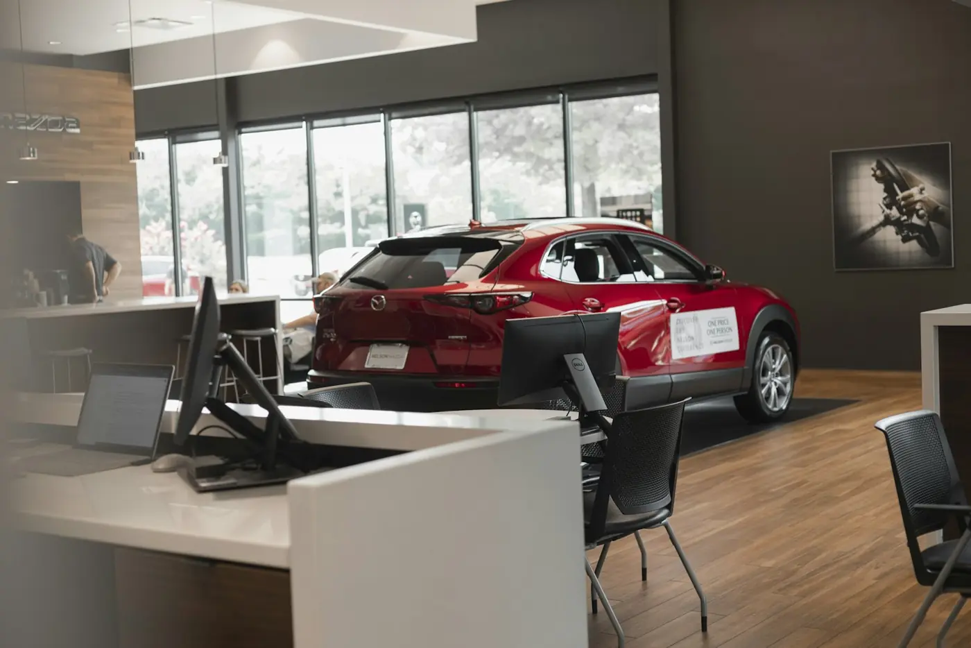 A red car on display inside a dealership showroom