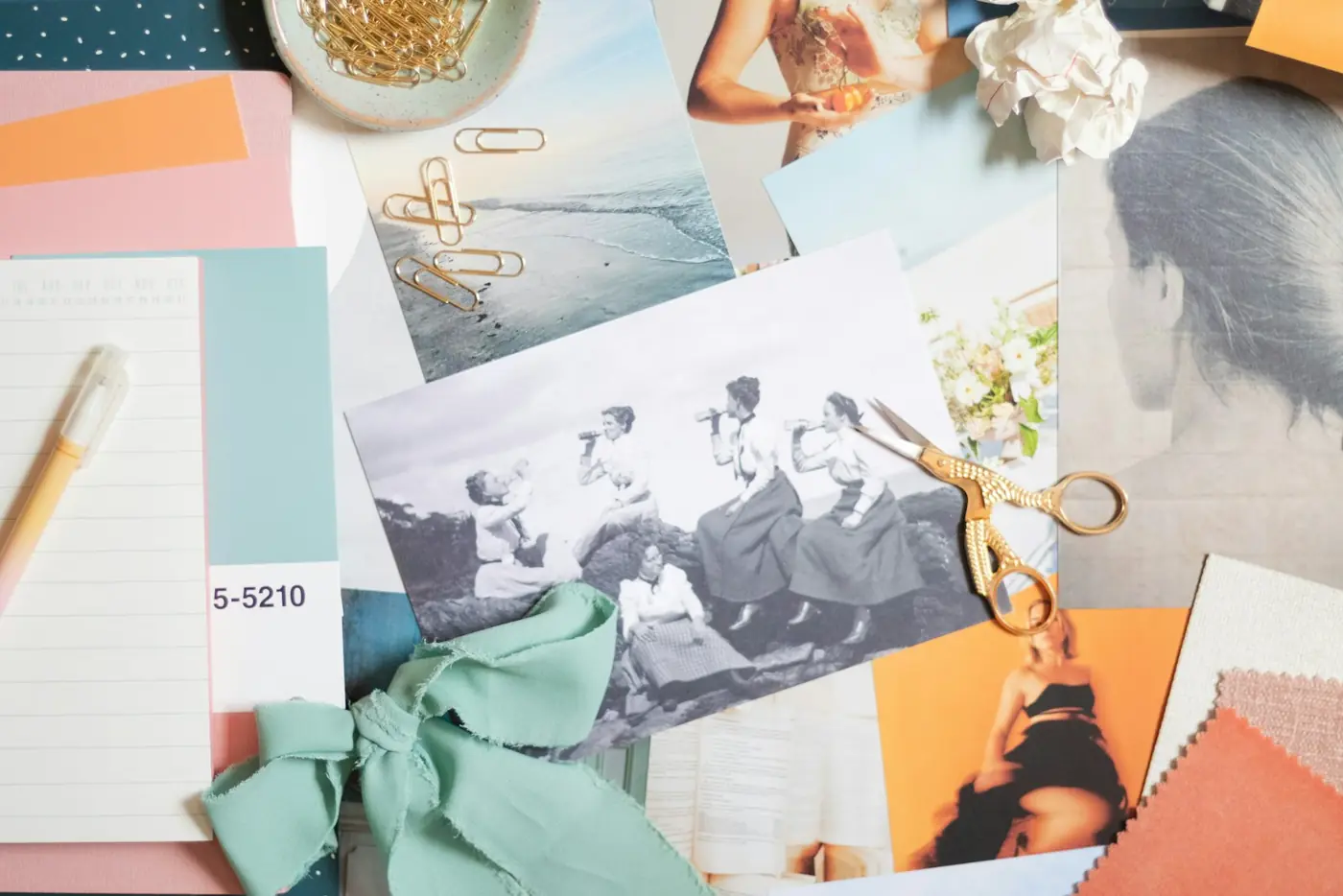 A brand moodboard of photos, colour swatches and ribbon on a table